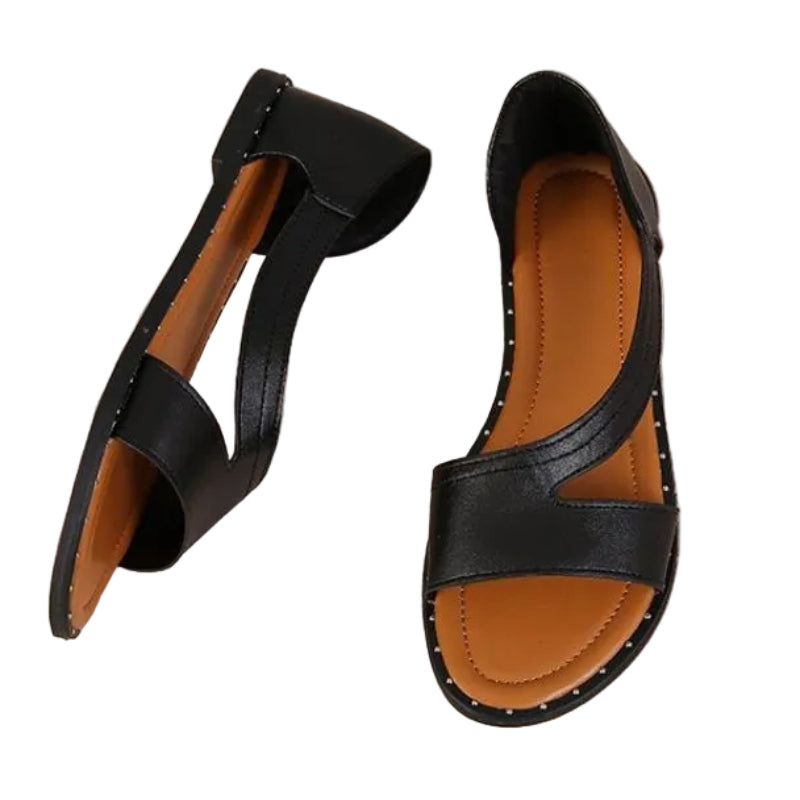 Black sandals with brown soles on a textured surface