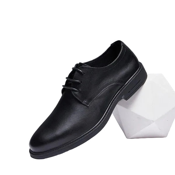 Black leather dress shoe on a white platform with a gray background
