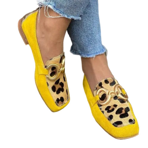 Person wearing yellow leopard print shoes with blue jeans and a yellow bag.