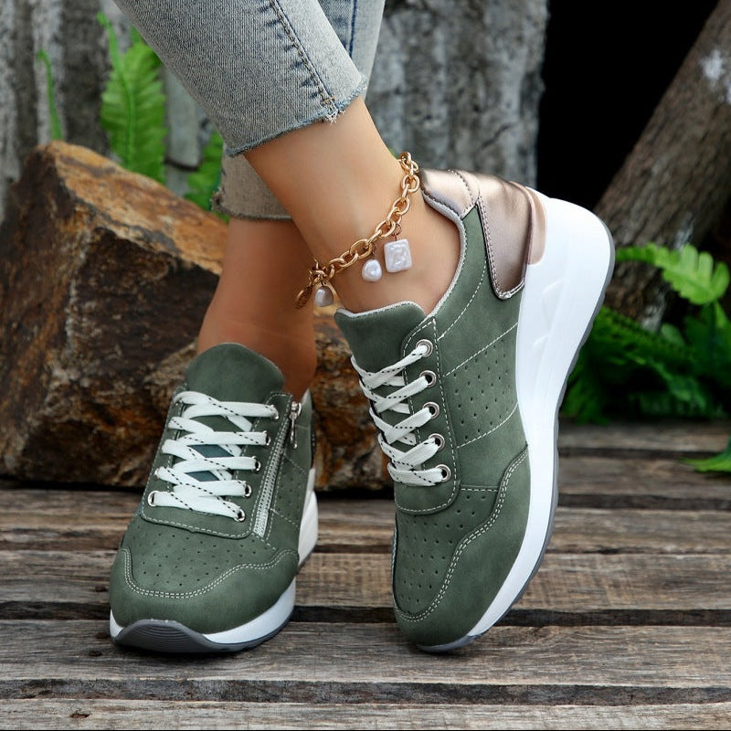 Green sneakers worn with light-colored pants on a wooden surface.
