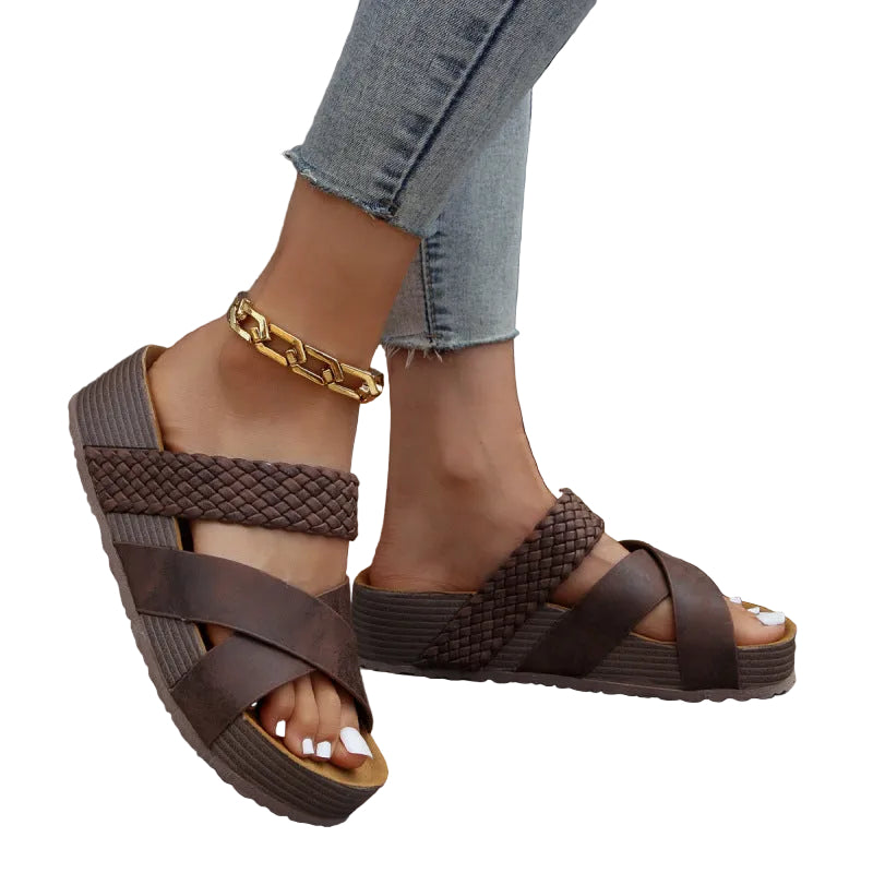 Brown sandals worn with light blue jeans against a natural background